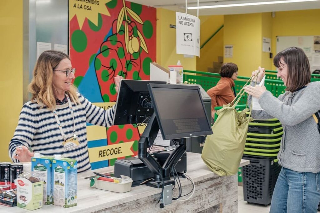 Una persona atendiendo a otra en un supermercado cooperativo